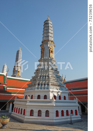 A small white tower that is located on the territory of the Temple of the Emerald Buddha. Religious architectural art of Southeast Asia. 73239656