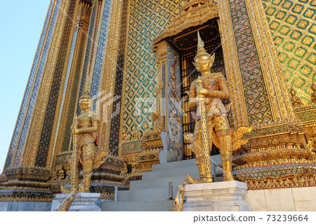 Two gilded sculptures of warriors guard the entrance to the magnificent Buddhist temple. 73239664