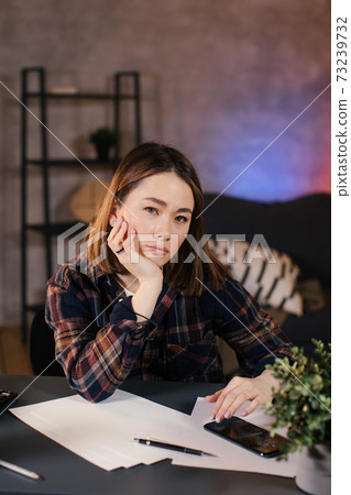 Asian girl trader working at home at the table, studying the chart 73239732