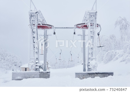 upper tower of the ski lift on a snow-covered hilltop among frosty trees upper tower of the ski lift on a snow-covered hilltop among frosty trees 73240847