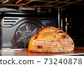 Baking sourdough bread in an oven. 73240878