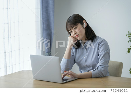 A young woman wearing a cheek stick and looking at a computer screen 73241011