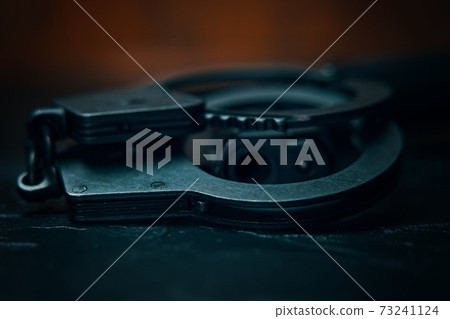 Handcuffs and the muzzle of hand gun close up. Handcuffs and the muzzle of hand gun close up. 73241124