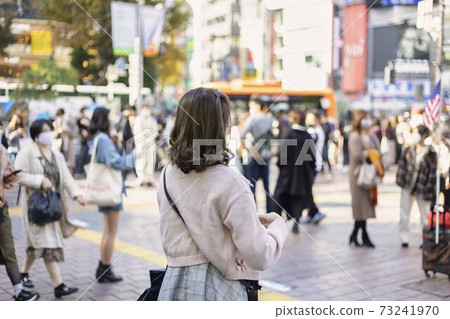 A young woman looking at a smartphone in front of Shibuya station A young woman looking at a smartphone in front of Shibuya station 73241970