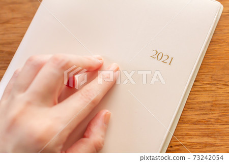 2021年元旦可愛日程本筆記本人們的手中 2021年元旦可愛日程本筆記本人們的手中 73242054