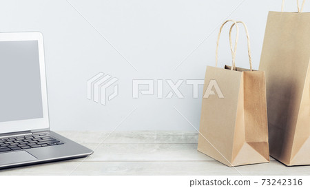 Laptop and paper shopping bags. Packages delivery online orders 73242316