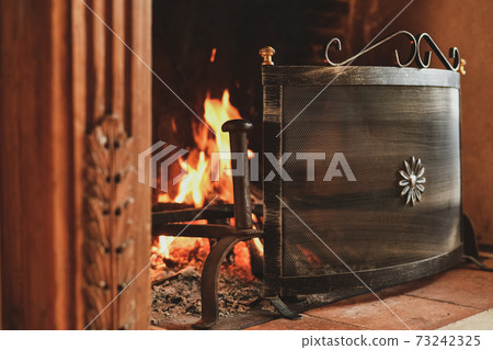Fire in a french old fireplace in a living room Fire in a french old fireplace in a living room 73242325