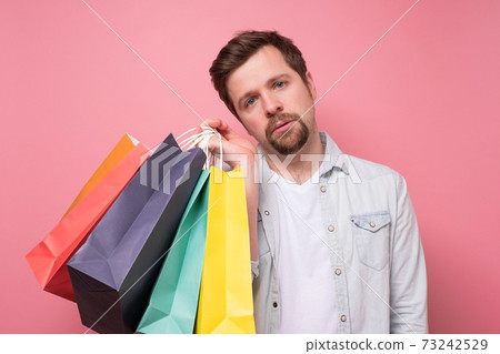 Tired caucasian guy holding a shopping bags. 73242529