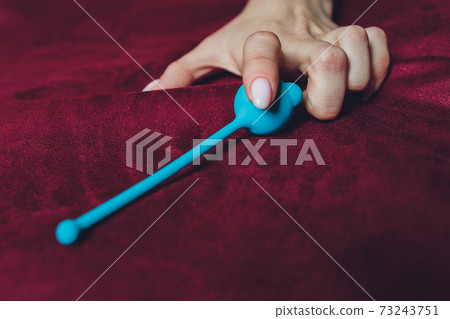 Woman holding anal balls in bed close-up. 73243751