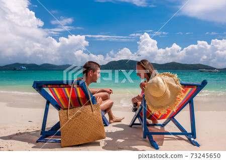 Couple on tropical beach in loungers 73245650