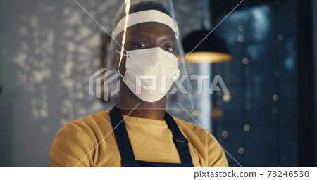 Black barista in face mask and shield in cafe Black barista in face mask and shield in cafe 73246530
