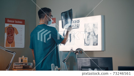 Doctor examining lungs X ray against lamp Doctor examining lungs X ray against lamp 73246561