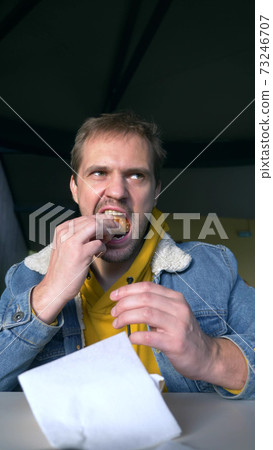portrait of angry man eating hamburger at fast food cafe portrait of angry man eating hamburger at fast food cafe 73246707