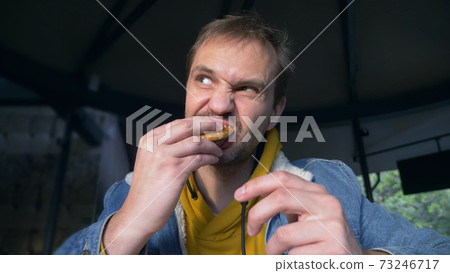 portrait of angry man eating hamburger at fast food cafe portrait of angry man eating hamburger at fast food cafe 73246717