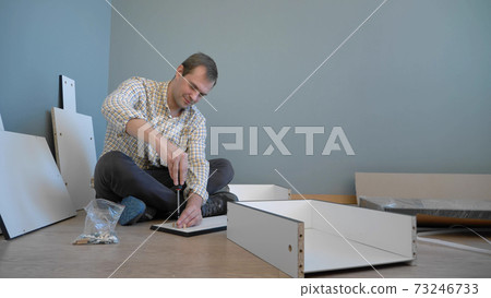 handsome man collects furniture at home in the room. copy space handsome man collects furniture at home in the room. copy space 73246733