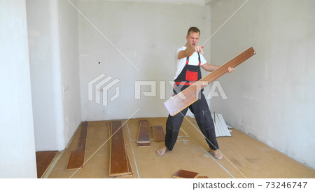 a man builder in overalls pretending to play the guitar on a laminate board a man builder in overalls pretending to play the guitar on a laminate board 73246747
