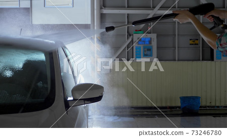 young woman washes a car at a self-service car wash. overall plan 73246780
