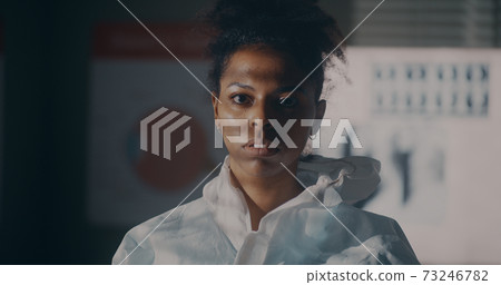 Ethnic medical practitioner taking off protective suit 73246782