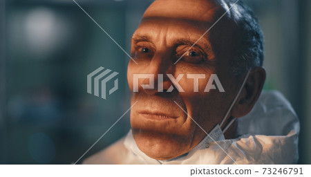 Tired mature doctor taking off protective suit Tired mature doctor taking off protective suit 73246791