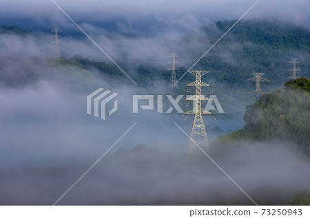 Electric transmission towers in fog Electric transmission towers in fog 73250943