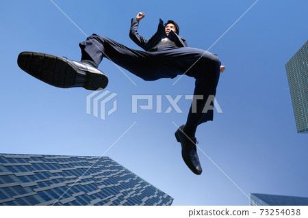 A businessman jumping against the blue sky A businessman jumping against the blue sky 73254038