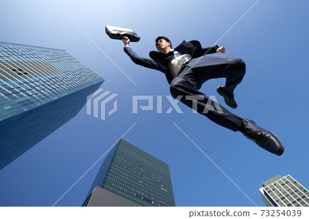 A businessman jumping against the blue sky A businessman jumping against the blue sky 73254039