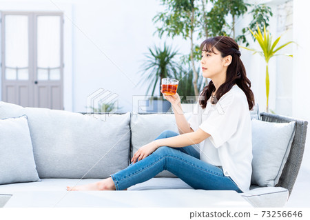 放鬆在庭院裡的沙發上的年輕女子 73256646