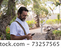 Portrait of adult caucasian man use mobile cellular smart phone outdoor at the park - modern people and connection technology - search the web with free wifi internet signal 73257565