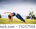 Beautiful young adult woman in balanced pilates exercise position outdoor - sport active people and healthy lifestyle concept - cheerful caucasian female do yoga 73257568