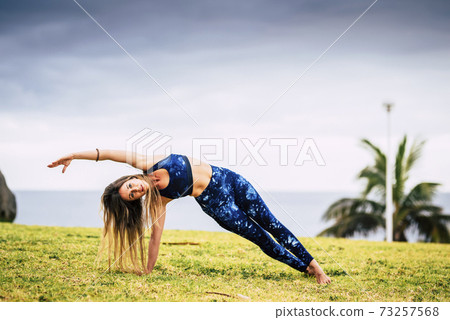 Beautiful young adult woman in balanced pilates exercise position outdoor - sport active people and healthy lifestyle concept - cheerful caucasian female do yoga Beautiful young adult woman in balanced pilates exercise position outdoor - sport active people and healthy lifestyle concept - cheerful caucasian female do yoga 73257568