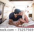 Love and travel with young caucasian couple kiss and love inside a trendy van vehicle during life or vacation leisure activity - concept of people together in tiny house alternative 73257569