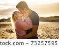 Kiss and love couple outdoor with two young man and woman kissing and hugging in a golden sunset background - people enjoy together forever life - concept of different ages male female 73257595