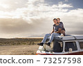 Young love couple sit down on a roof van enjoy travel lifestyle and holiday vacation together - concept of van life and free alternative trip with pretty couple enjoying outdoor and hug 73257598