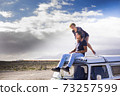 Happy couple enjoy the roof van together having fun in travel holiday alternative vacation - people together in road trip with transport vehicle and love life concept with blue sjy in background and 73257599