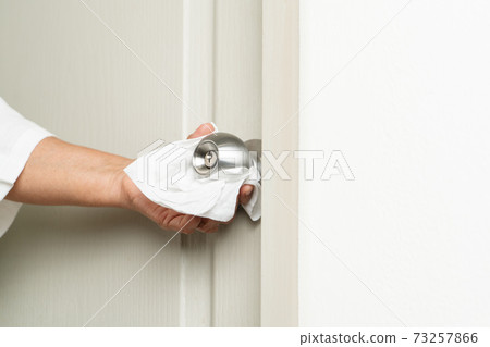 Cleaning door knob with alcohol spray for Covid-19 Coronavirus prevention 73257866