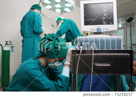 Team of professional surgeons performing operation in hospital , they are holding defibrillator and help while patient will die operation room at hospital 73258257