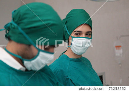 surgeons team wearing safety masks performing operation. Medicine concept surgeons team wearing safety masks performing operation. Medicine concept 73258262