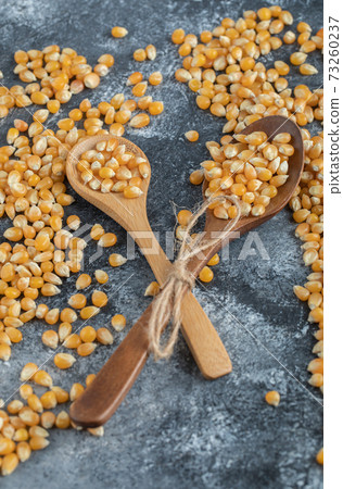 Wooden spoons of sweet corns on marble background 73260237