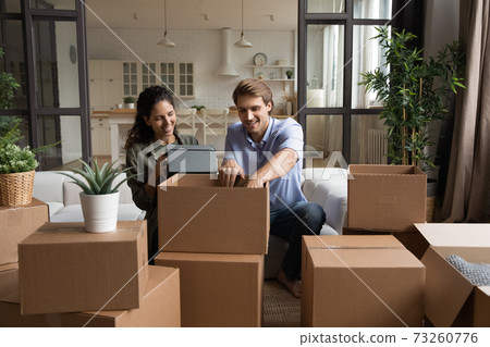 Excited couple unpacking boxes moving in together 73260776