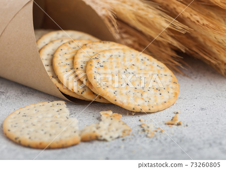Round organic crispy wheat and corn flatbread crackers with raw wheat on light background. 73260805