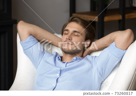 Young man relax in chair sleeping at home 73260817