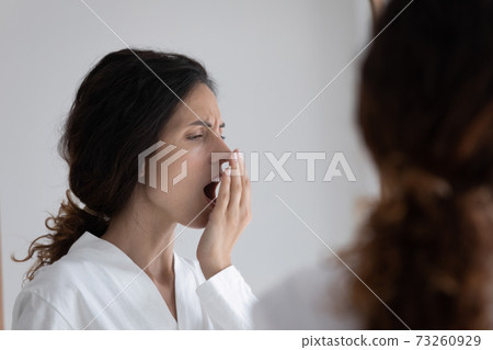 Young woman check freshness of breath in home bath Young woman check freshness of breath in home bath 73260929