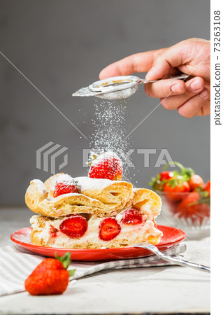 A piece of cake on red plate with strawberries A piece of cake on red plate with strawberries 73263108