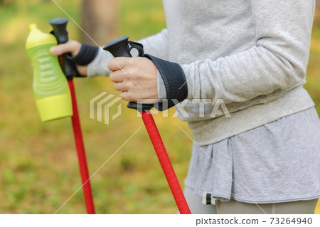 Woman with trekking poles and bottle of water Woman with trekking poles and bottle of water 73264940