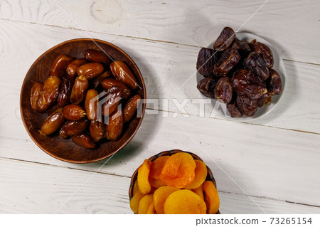 Dried apricots and dates fruit on white wooden table. Top view Dried apricots and dates fruit on white wooden table. Top view 73265154