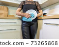 Adult woman wiping plates at kitchen 73265868