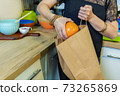 Woman take out fruits from paper bag 73265869