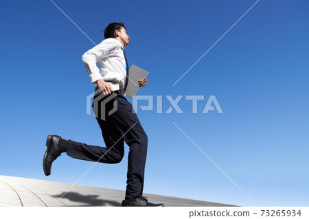 Young man running under the blue sky 73265934