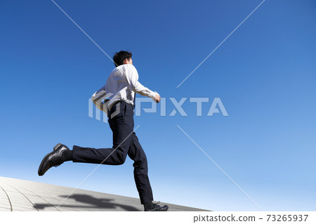 Young man running under the blue sky 73265937