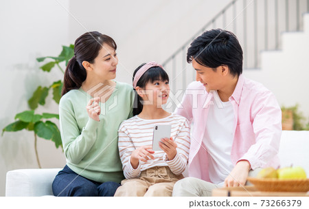 A young family looking at a smartphone in the living room A young family looking at a smartphone in the living room 73266379